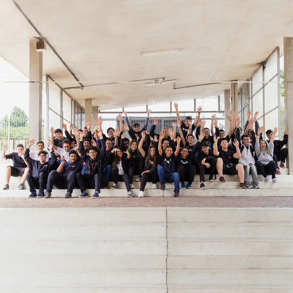 Un grand groupe d'étudiants agitent leurs mains en l'air.