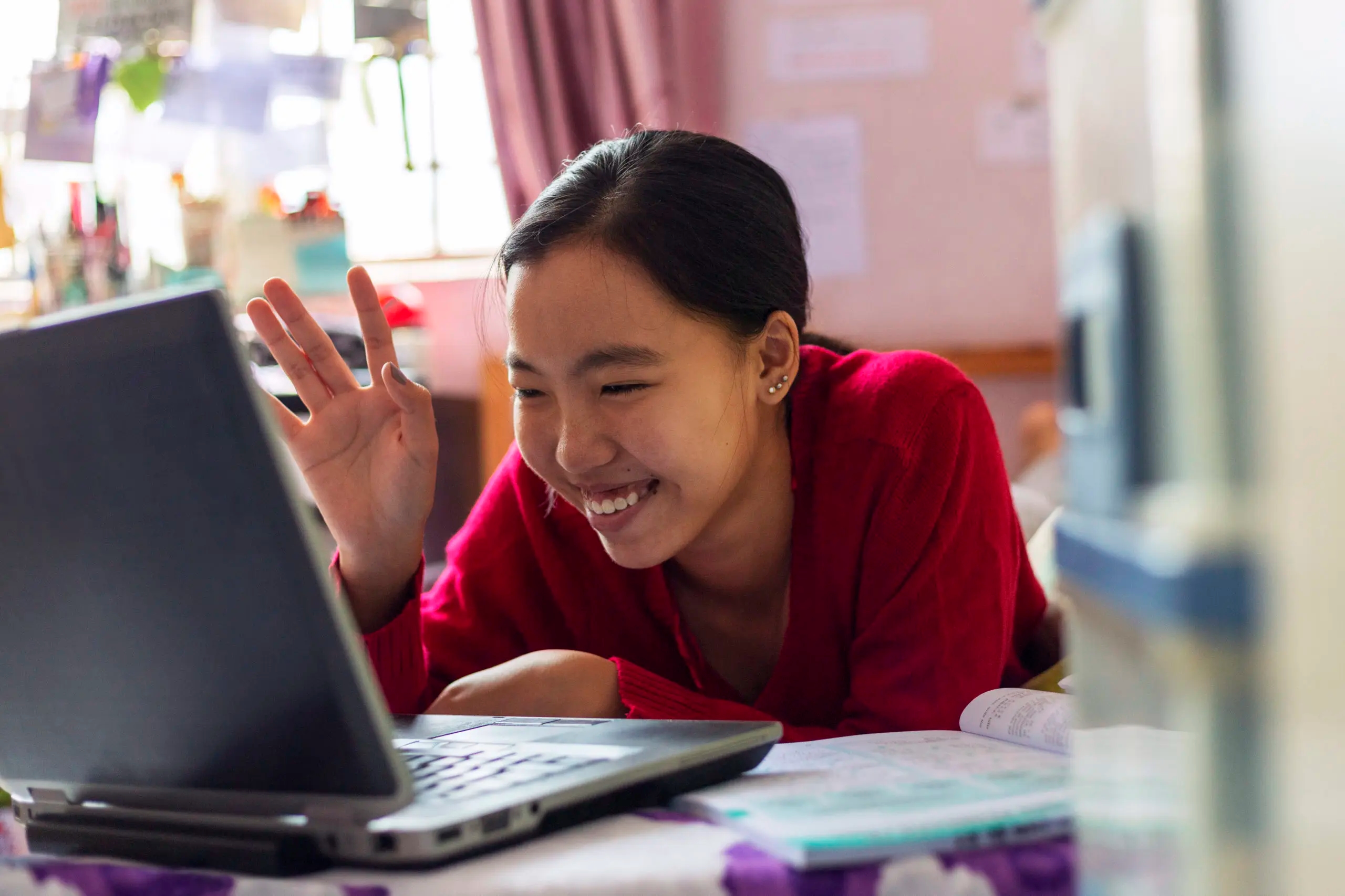 Young girl uses her laptop teleconferencing in the house