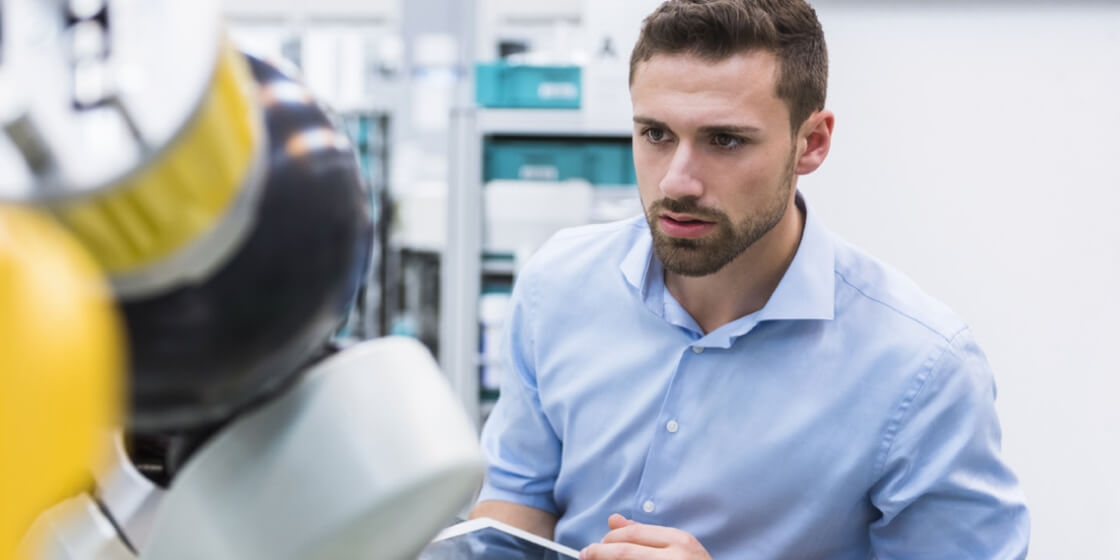 Young man in front of a robot working