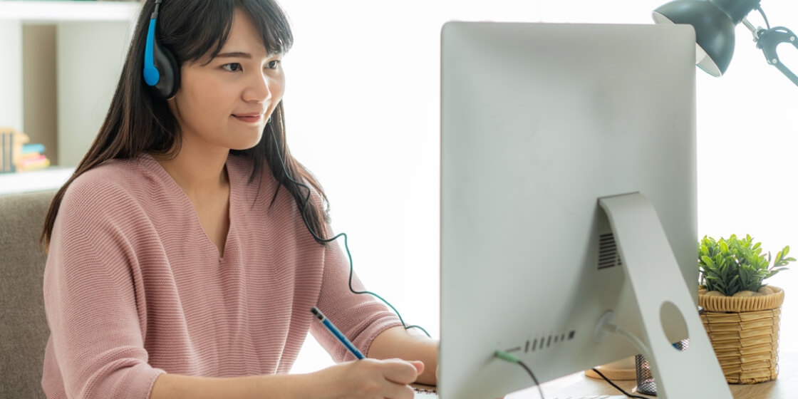 Young woman sitting at the desk and working in front of a computer