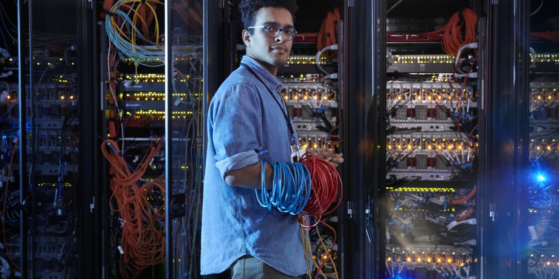 Young man wearing glasses doing data center maintenance