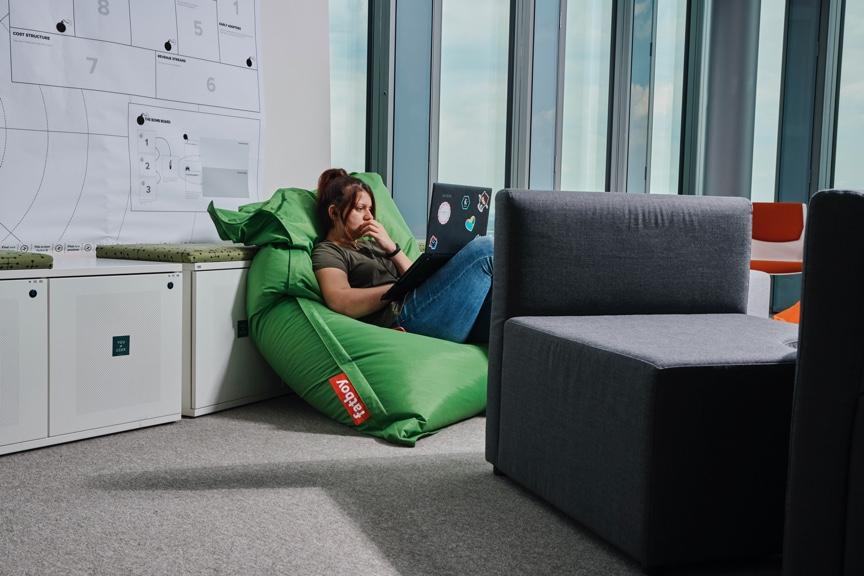 Woman working on laptop sitting in bean bag chair at office